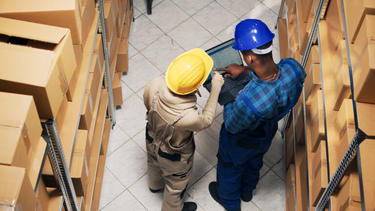 Contact 1 Stma diverse employees analyzing inventory list laptop counting products boxes storage room shelves young people using device work stock logistics delivery service